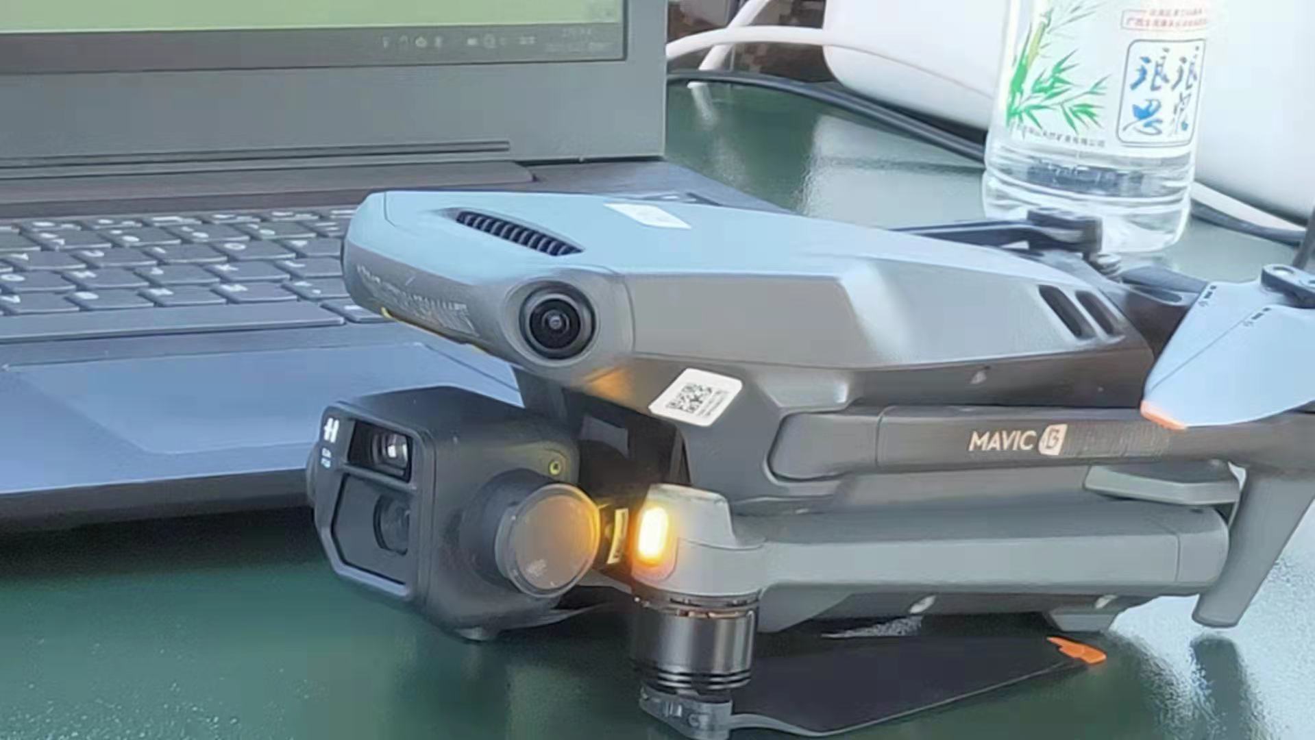 real life image of a mavic 3 infront of a laptop and a bottle